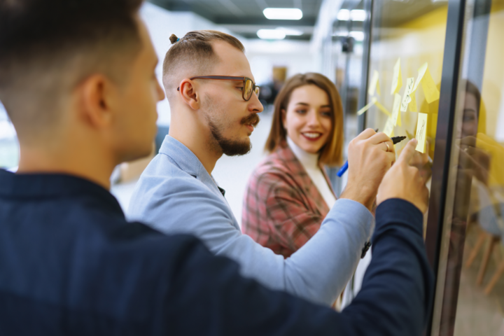 Young business people discussing and planning strategy for overcoming bottlenecks in business Front of glass wall marker and stickers.